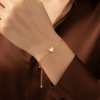 Dil — Gold Heart Charm Bracelet worn on wrist Dil — Gold Heart Charm Bracelet worn on wrist
